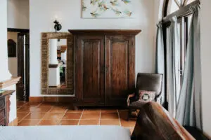 a cupboard, chair, and mirror in a bedroom