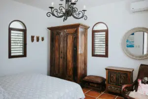 a wooden cupboard, side table, round mirror in bedroom